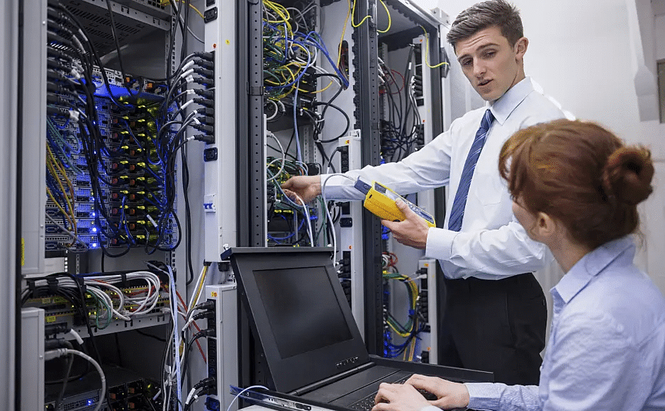 A man and woman working in a server room