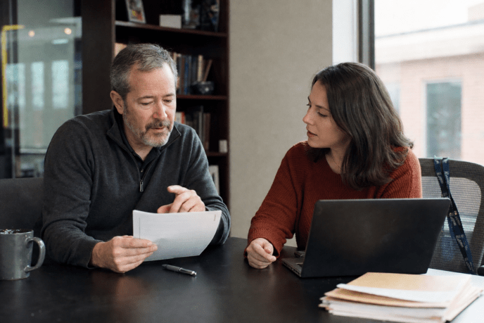 Manager and employee reviewing a printed AI usage policy at a desk